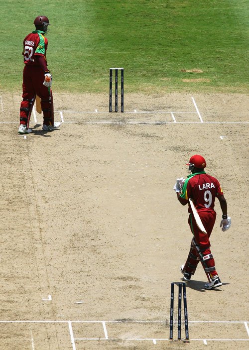 Brian Lara heads for the pavilion after being run-out, while Marlon Samuels can only reflect on w