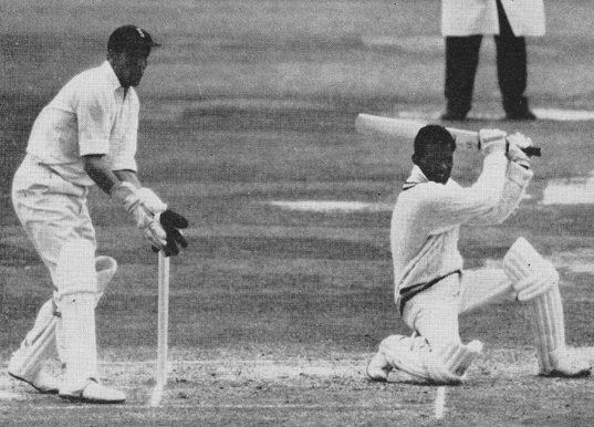 The defiant Kunderan goes down on one knee to drive Hobbs. Murray who equalled a world wicket keeping record is poised over the stumps.